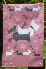 Load image into Gallery viewer, Burgundy tea towel with dog and bone patterns on a line
