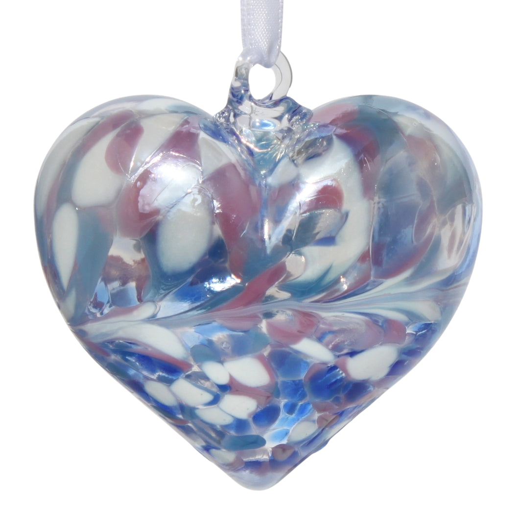 A mouth-blown glass heart-shaped decoration with an iridescent finish in blue, pink, and white colors, hanging from a white satin ribbon.