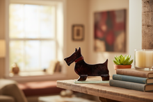 Load image into Gallery viewer, Decorative dog figurine on a table with books and a candle in a cosy room.
